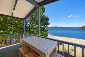 a porch with a bench and a view of a beach at Reflections Burrinjuck Waters - Holiday Park in Bookham