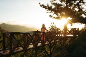 a woman walking on a bridge with the sun in the background at Camping- Sanagua Lodge in El Copé