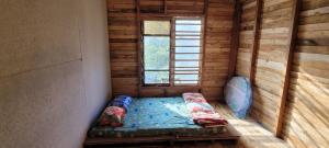 a small bed in a room with a window at Mộc Tín Farmstay in Lạc Dương