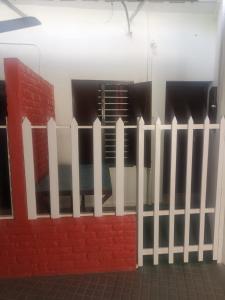 a white fence next to a red brick wall at Railviewtouristhome in Varkala +1 photo