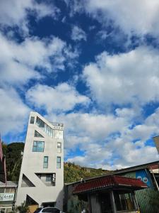 a white building with a cloudy sky in the background at Shan Da Ke Qi Min Su in Zhonghe