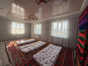 two beds in a room with curtains and windows at Tunduk House14 in Bash-Kayyngdy