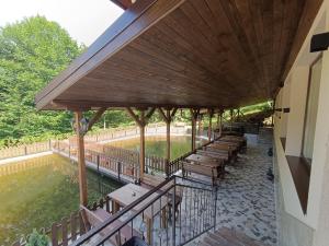 a deck with tables and benches next to a pond at Комплекс Кантона in Razhishte