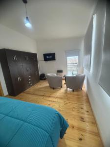 a bedroom with a bed and two chairs and a table at Acordes de Gaitas - Departamento 3 in Malargüe
