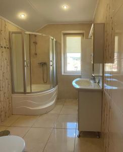 a bathroom with a shower and a tub and a sink at Passage Apartments 10a in Skhidnitsa