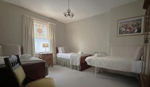 a room with two beds and a chair and a window at Old Bishop's Quarters in Hobart