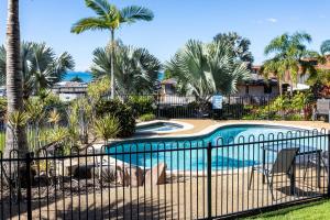 a swimming pool with a fence and palm trees at Sea Air 2 in Yeppoon