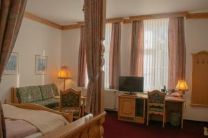 a bedroom with a bed and a couch and a television at Pension Haus Marga in Wernigerode