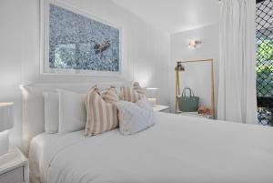 a white bedroom with a large white bed with pillows at Suntan at Sunshine in Sunshine Beach +26 photos