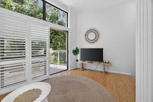 a living room with a tv and a large window at Suntan at Sunshine in Sunshine Beach