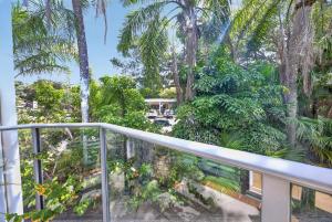 a balcony with palm trees and a house at Suntan at Sunshine in Sunshine Beach
