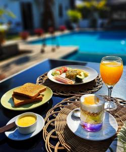 a table with plates of food and a glass of orange juice at Guesthouse MALAGUETA INN II in Maputo