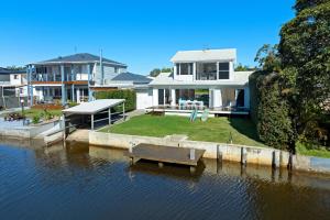 a house on the water with a boat in the water at The River Retreat in Sussex Inlet