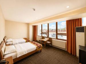 a hotel room with two beds and a large window at Margad Hotel in Ulaanbaatar