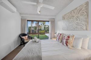 a bedroom with a white bed with a chair and a window at The Noosa Apartments in Noosa Heads +234 photos