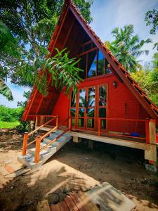a red house with glass doors and a porch at Paddy field Whispering wind Cabin in Ahangama Nakanda