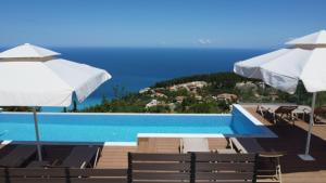 a swimming pool with chairs and umbrellas at Lefkada Sunset Villa in Kalamitsi