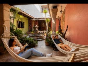 a man and woman sitting in hammocks in a courtyard at Hostal Central Oaxaca in Oaxaca City
