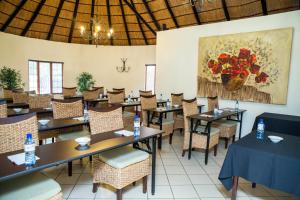 a restaurant with tables and chairs and a painting of flowers at Rustenburg Boutique Hotel in Rustenburg