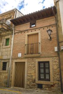 a brick building with a balcony and a clock on it at APARTAMENTO RURAL ABUELO EMILIO in Tornavacas