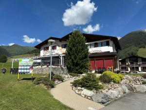 a large building with a tree in front of it at Catrina Lodge in Disentis