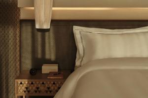 a bedroom with a white bed and a nightstand with a clock at Rosewood AMAALA in Amala