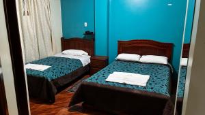 a room with two beds and a blue wall at Hotel Grant Ruiseñor in Chambo +3 photos
