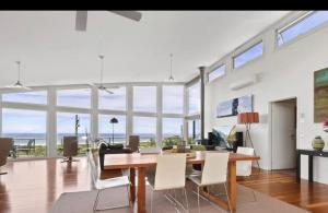 a dining room with a table and chairs and windows at Marcail Views Lakes Entrance in Lakes Entrance