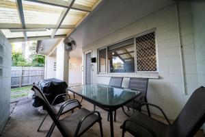 a patio with a glass table and chairs at Comfy Kirwan Getaway in Ross River