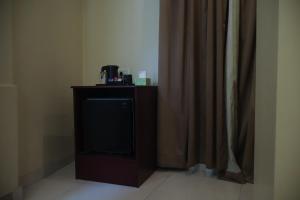 a tv sitting on a stand next to a curtain at The Hotel Chettungal in Angamaly