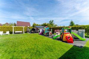 a playground in a grassy yard with a slide at Villa Konwalia in Grzybowo