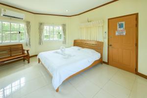 a bedroom with a bed with white sheets and a door at Reaunnapa Resort in Ban Nong Kham