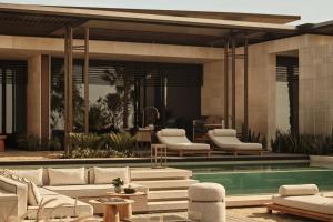 a pool with white lounge chairs and a swimming pool at Rosewood AMAALA in Amala