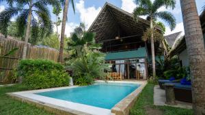 a swimming pool in front of a house with palm trees at Buko Beach Resort in El Nido