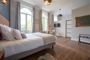 a bedroom with a large white bed and windows at Domaine du Béron - Chateau et gites in Cappelle-en-Pévèle