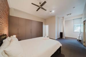 a bedroom with a white bed and a ceiling fan at Flinders 2 bed apartment near the Strand in Townsville