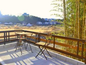 Ein Tisch und Stühle auf einem Balkon mit Blick auf ein Feld in der Unterkunft まち宿-machi yard- in Nakatsugawa