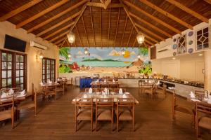a restaurant with tables and chairs and a mural at Golden Tulip Goa Mandrem in Mandrem