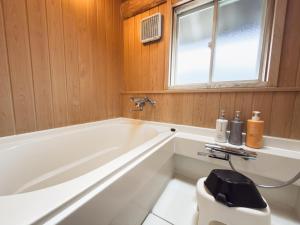 a bathroom with a white tub and a window at Kawazu Log House in Kawazu