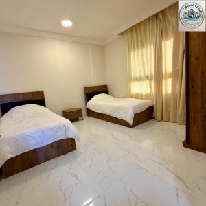 two beds in a room with a marble floor at المنصور 3 in Salalah