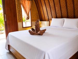 a stuffed animal sitting on top of a bed at Warna Cottage in Gili Trawangan
