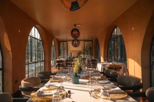a dining room with tables and chairs and windows at Giraffe Manor Tanzania in Usa