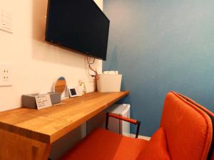 ein Zimmer mit einem Schreibtisch und einem Fernseher an der Wand in der Unterkunft まち宿-machi yard- in Nakatsugawa