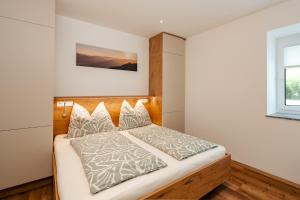 a bedroom with a bed with a wooden headboard at Peak9 Apartment in Greifenburg