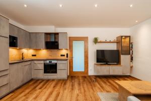 a large kitchen with wooden floors and a flat screen tv at Peak9 Apartment in Greifenburg +6 photos