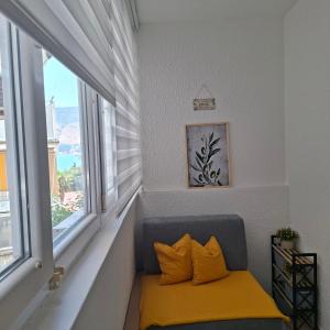 a bench with two yellow pillows in a room with windows at Top Topla - Herceg Novi in Topla