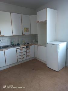 an empty kitchen with white cabinets and a refrigerator at Tattara School Room 2 in Nakkila