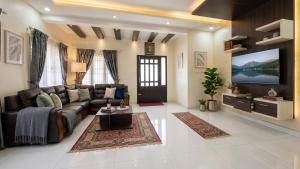 a living room with a couch and a flat screen tv at The Grand Villa Kochi in Cochin