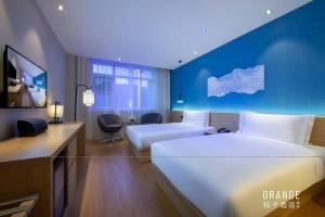 a hotel room with two beds and a blue wall at Orange Hotel Beijing Summer Palace in Beijing