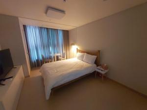 a bedroom with a white bed and a window at Guri 365 Stay in Guri